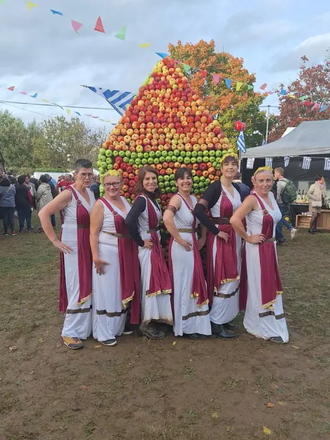 Groupe costumé en tenue grecque devant la pyramide de pommes
